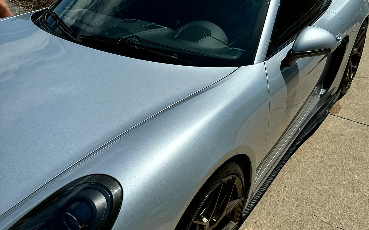 A silver Porsche detailed and coated in a residential driveway