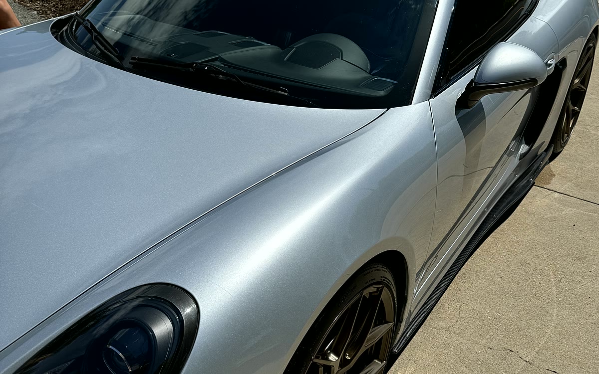 A silver Porsche detailed and coated in a residential driveway